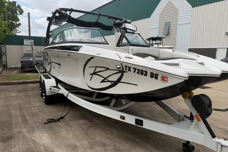 Slide: The Image of 2010 Tigé RZ2 boat on trailer, parked outdoors near industrial buildings. - 3