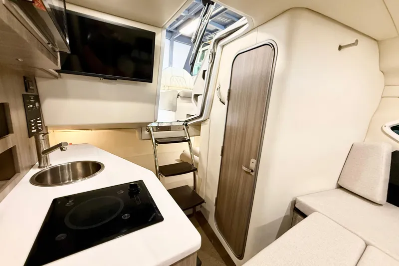 Slide: The Image of Interior of a 2021 Regal 26 Express boat featuring a kitchenette and seating area. - 18