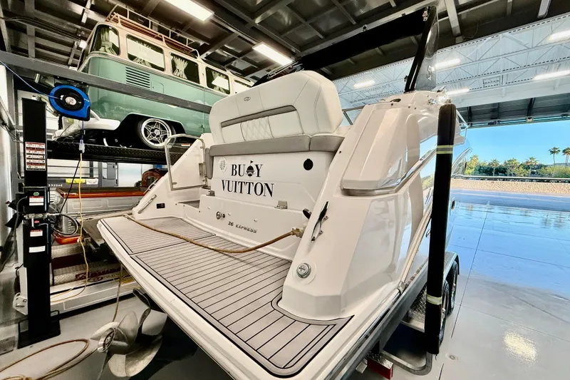 Slide: The Image of 2021 Regal 26 Express boat in garage, with vintage vehicle above on lift. - 2