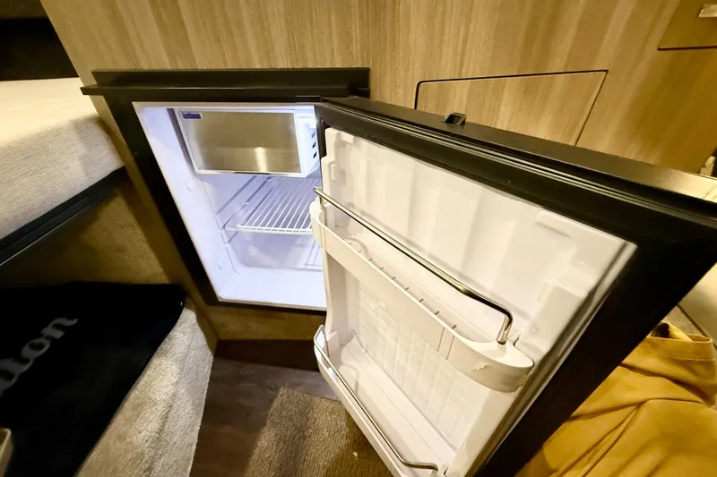 Slide: The Image of Compact refrigerator inside 2021 Regal 26 Express boat cabin, open door showing interior shelves. - 23