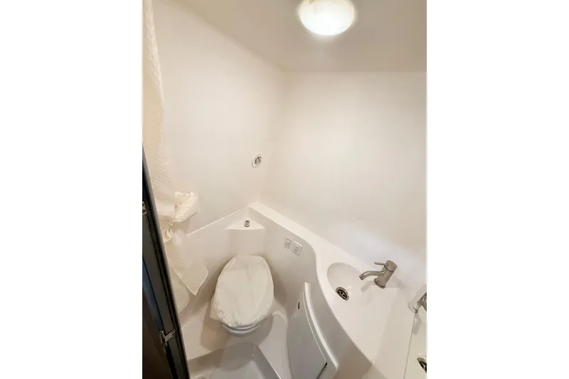 Slide: The Image of 2021 Regal 26 Express boat bathroom with compact toilet and sink. - 26