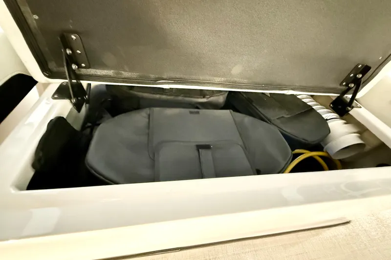 Slide: The Image of Storage compartment in a 2021 Regal 26 Express boat, containing bags and coiled hoses. - 41