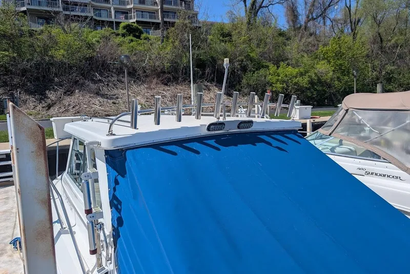 Slide: The Image of 1998 Cherokee 270 Sportsman boat with blue canopy docked near greenery. - 12