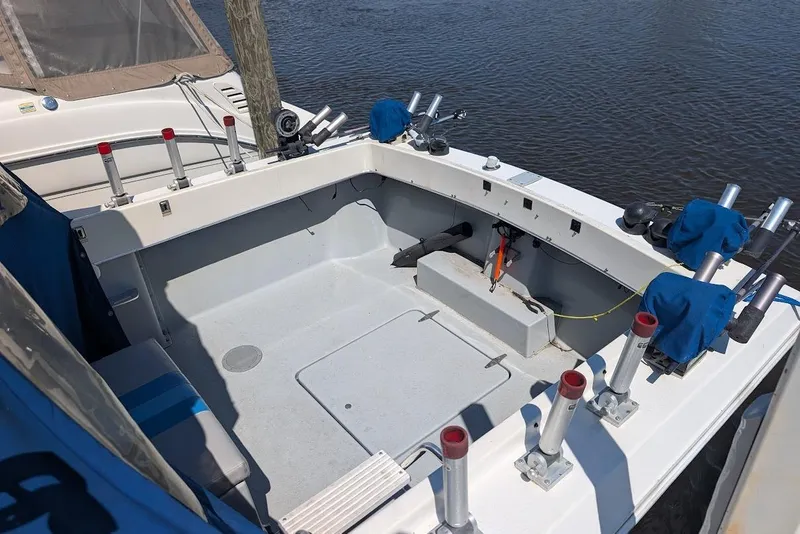 Slide: The Image of 1998 Cherokee 270 Sportsman boat deck with fishing rod holders, docked by the water. - 13