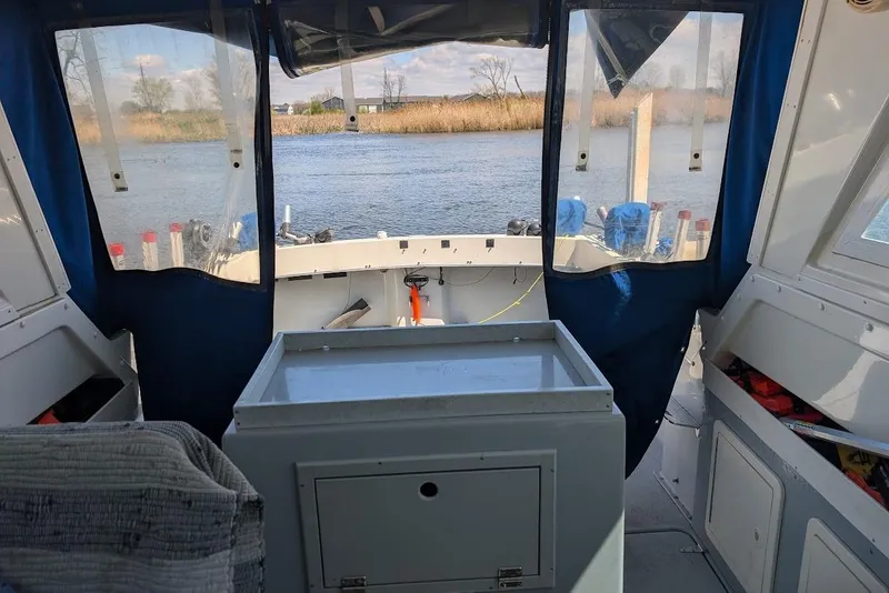 Slide: The Image of Interior view of a 1998 Cherokee 270 Sportsman boat with blue curtains and river backdrop. - 25