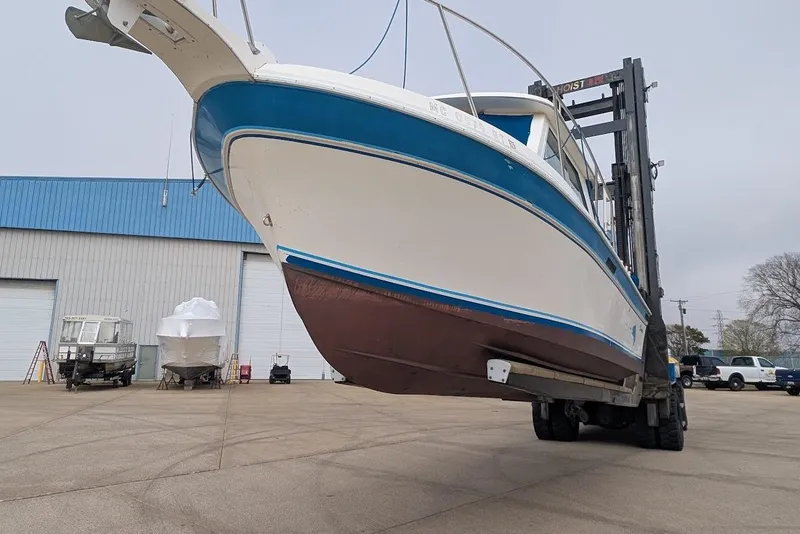 Slide: The Image of 1998 Cherokee 270 Sportsman boat lifted by forklift at marina. - 48