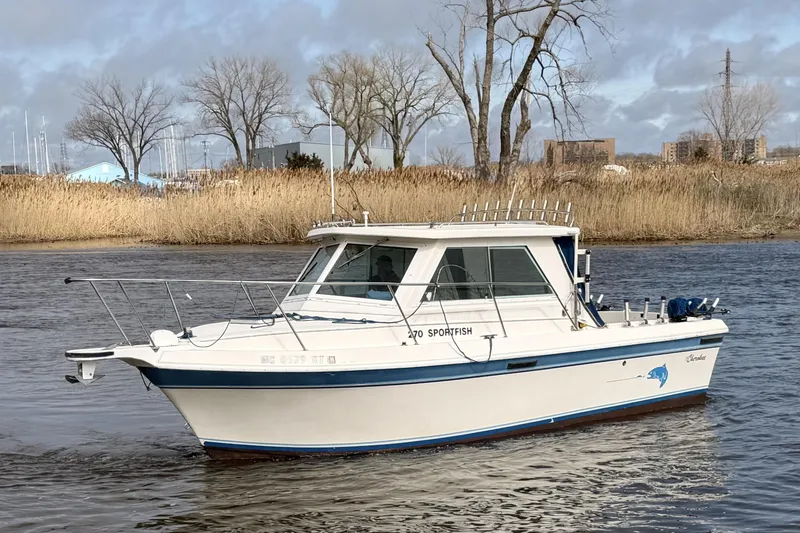 Slide: The Image of 1998 Cherokee 270 Sportsman boat cruising on a river with reeds and trees in the background. - 5