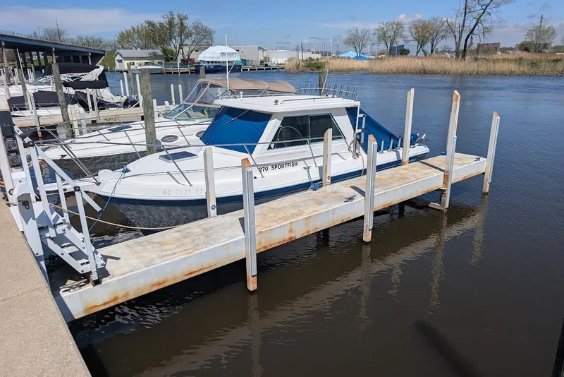 Slide: The Image of 1998 Cherokee 270 Sportsman boat docked at a marina, surrounded by calm water and other vessels. - 7