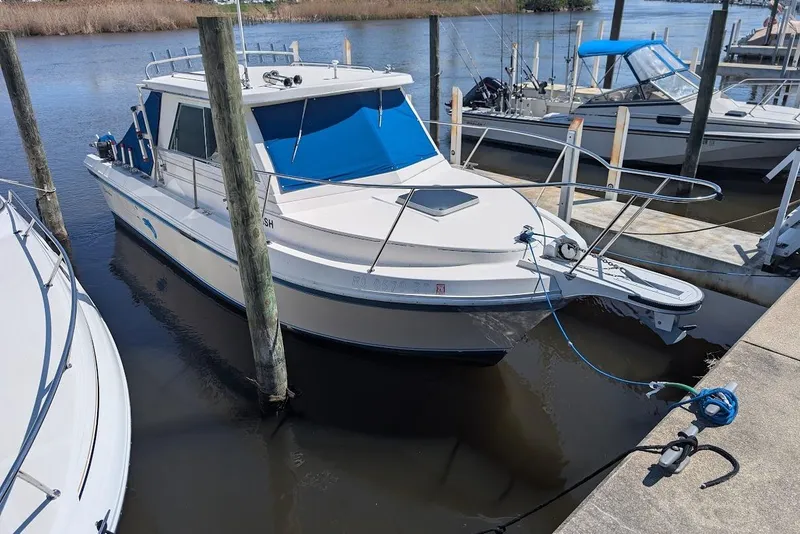 Slide: The Image of 1998 Cherokee 270 Sportsman boat docked at a marina, featuring a blue canopy. - 8