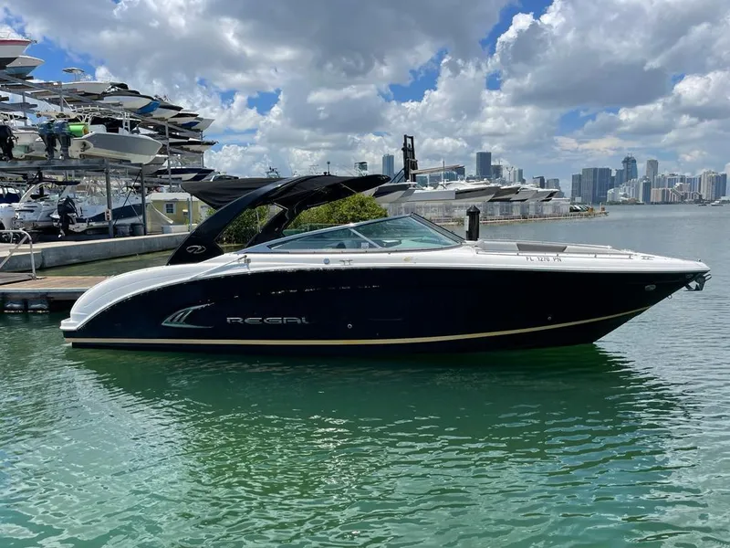 The Image of 2013 Regal 3200 Bowrider boat docked in a marina with city skyline. - 0