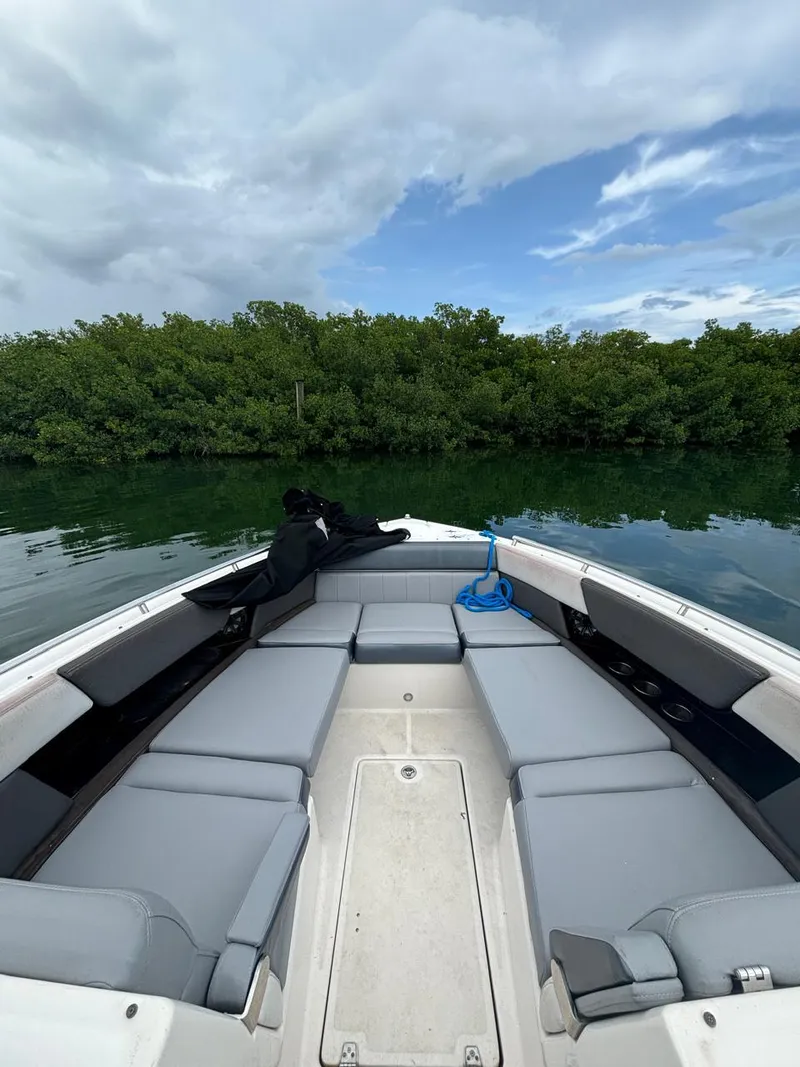 Slide: The Image of 2013 Regal 3200 Bowrider on calm water, surrounded by lush greenery. - 6