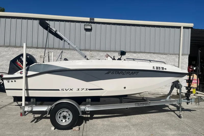 The Image of 2025 Starcraft SVX 171 OB boat on trailer, parked outside a building. - 0