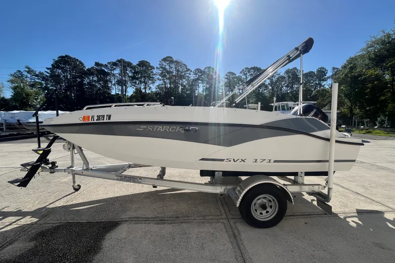 Slide: The Image of 2025 Starcraft SVX 171 OB boat on trailer, parked outdoors under clear blue sky. - 22