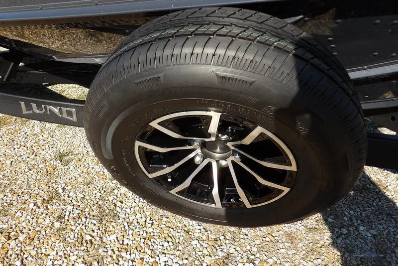 Slide: The Image of 2026 Lund 2075 Pro-V Bass XS trailer wheel on gravel surface. - 21