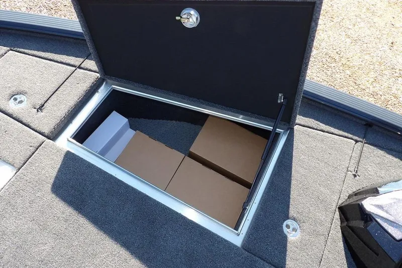 Slide: The Image of Storage compartment in 2026 Lund 2075 Pro-V Bass XS boat, featuring carpeted interior and secure latch. - 36