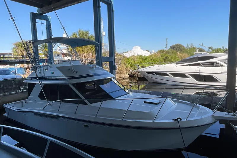 The Image of 1990 Chris-Craft 392 Commander docked under a covered marina, with another yacht nearby. - 0