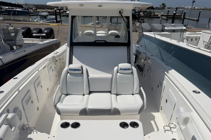Slide: The Image of 2018 Everglades 355 Center Console boat interior with seating and cup holders at a marina. - 16