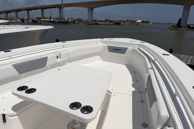 Slide: The Image of 2018 Everglades 355 Center Console boat with spacious seating and table, docked near a bridge. - 17