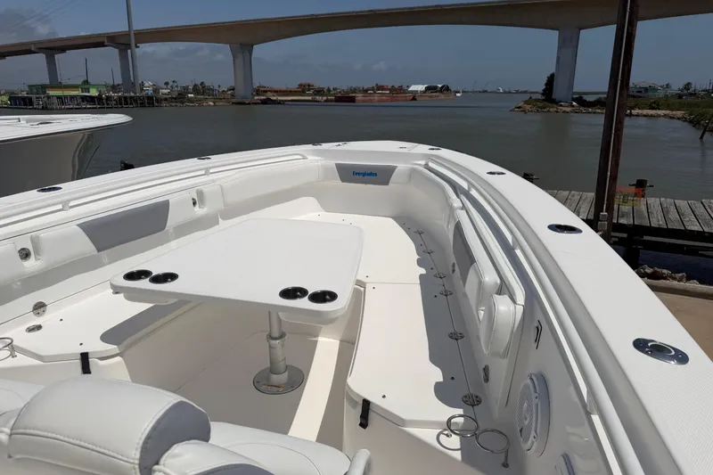Slide: The Image of 2018 Everglades 355 Center Console boat with seating and table, docked near a bridge. - 18