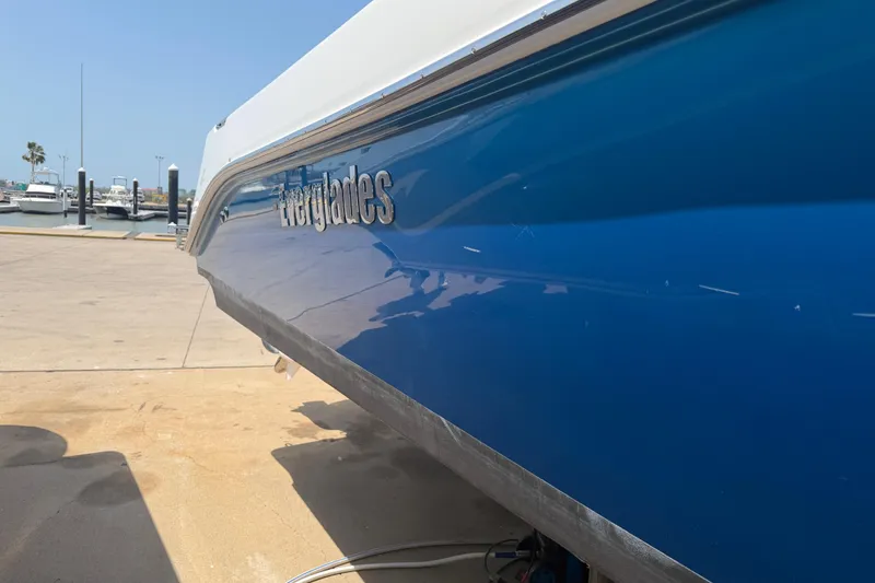 Slide: The Image of 2018 Everglades 355 Center Console boat docked, showcasing sleek blue hull design. - 6