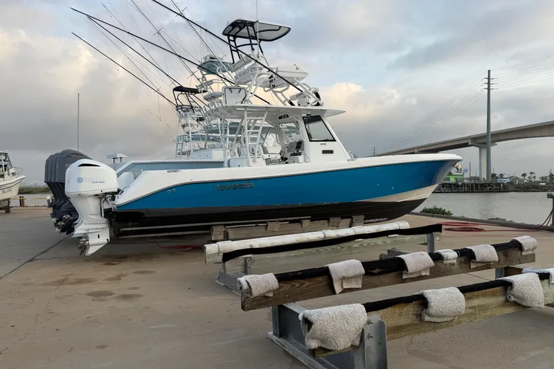Slide: The Image of 2018 Everglades 355 Center Console boat on dock, featuring Yamaha engines, under cloudy sky. - 75