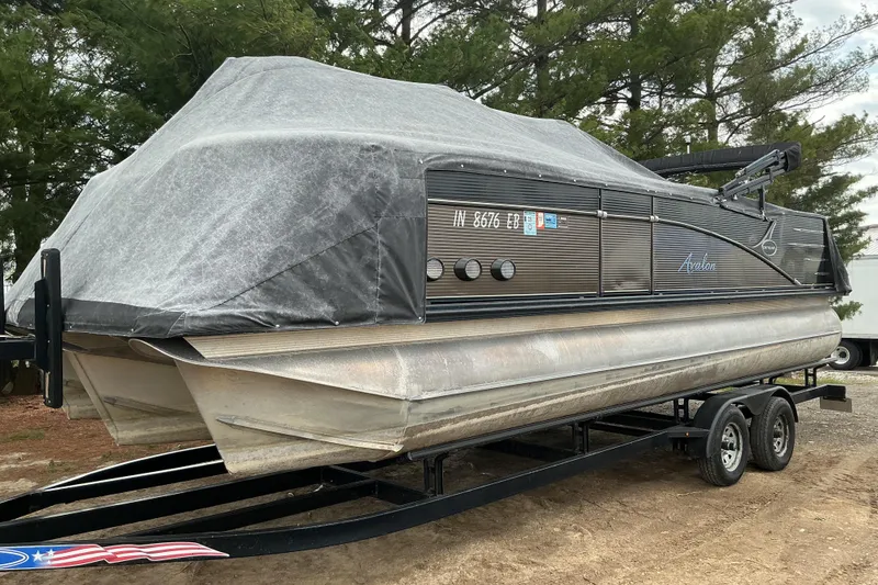 Slide: The Image of 2019 Avalon Catalina Platinum Rear J Lounge boat covered on trailer, parked outdoors. - 16
