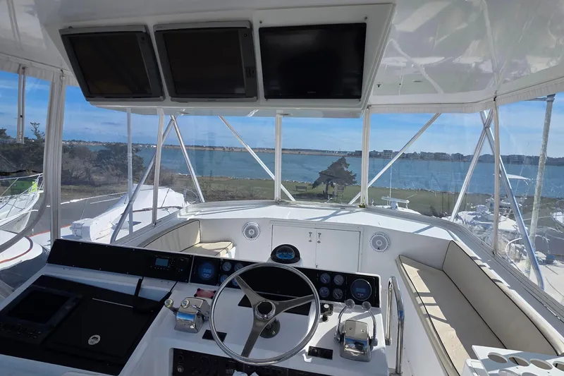 Slide: The Image of Cockpit view of 1989 Hatteras 52 Convertible yacht overlooking serene waterfront. - 36