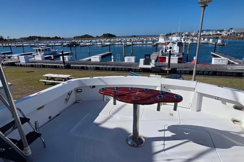 Slide: The Image of 1989 Hatteras 52 Convertible yacht at marina, featuring spacious deck and scenic waterfront view. - 32