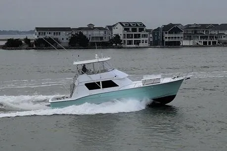 Slide: The Image of 1989 Hatteras 52 Convertible yacht cruising near waterfront homes. - 6