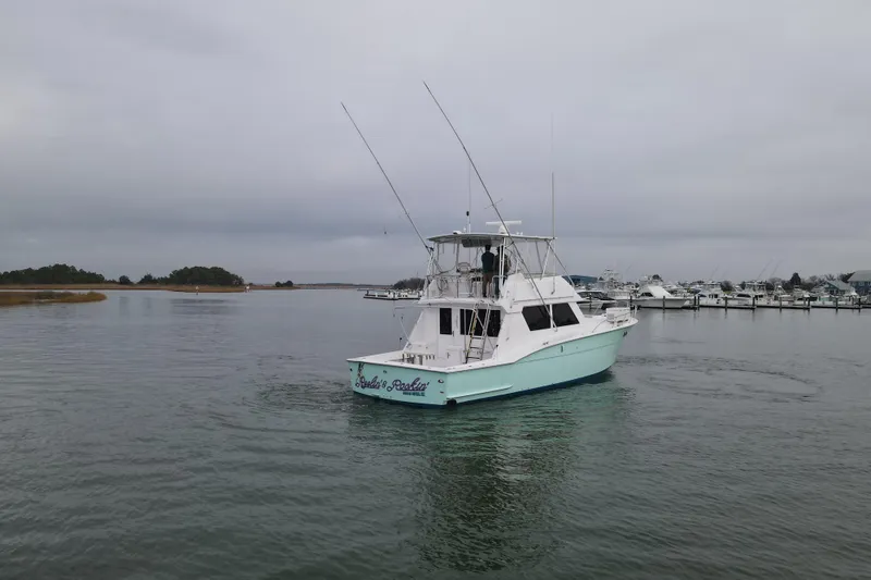 Slide: The Image of 1989 Hatteras 52 Convertible yacht cruising in a calm marina under overcast skies. - 3