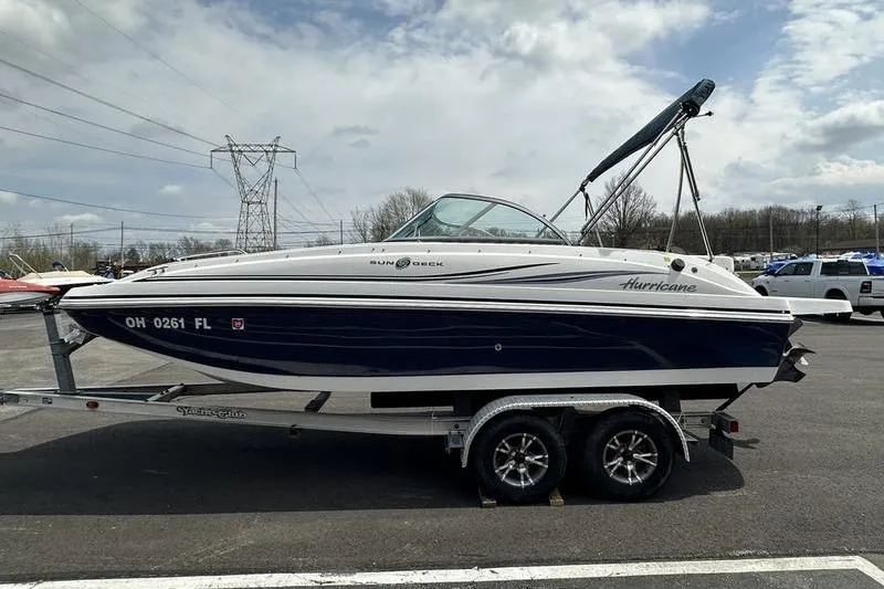 Slide: The Image of 2014 Hurricane SunDeck 187 IO boat on trailer, parked outdoors under cloudy sky. - 13