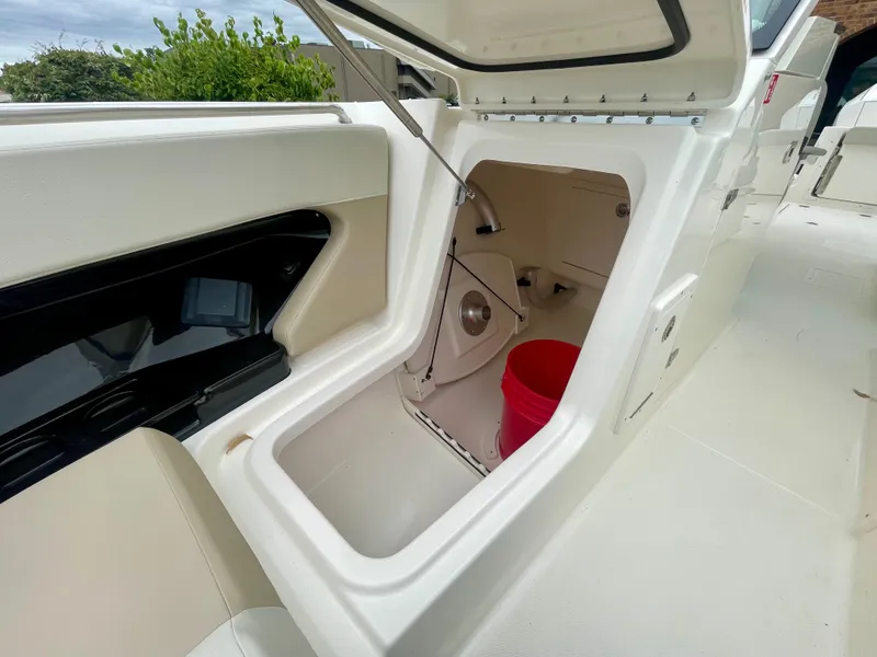 Slide: The Image of A storage compartment on a Boston Whaler 280 Vantage boat with a red bucket inside. - 32