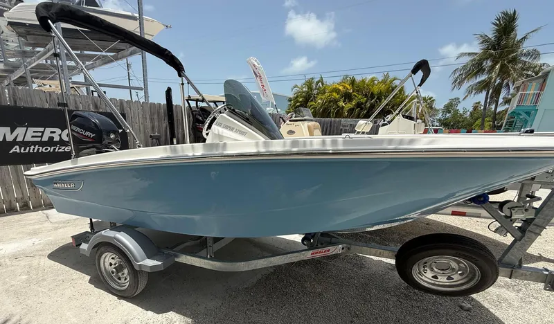 Slide: The Image of A blue 2026 Boston Whaler 130 Super Sport on a trailer. Palm trees in the background. - 2