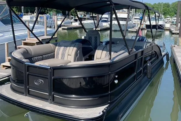 Slide: The Image of 2021 Barletta L25UE pontoon boat docked at marina, featuring spacious seating and canopy. - 2