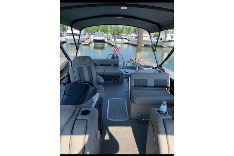 Slide: The Image of 2021 Barletta L25UE pontoon boat interior at marina, featuring luxurious seating and canopy. - 6