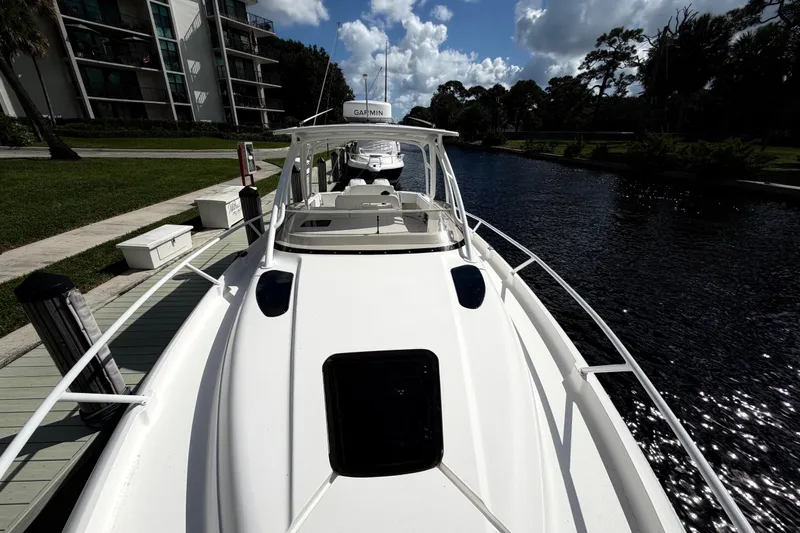 Slide: The Image of 2008 Intrepid 350 Center Console boat docked by a canal under a partly cloudy sky. - 26