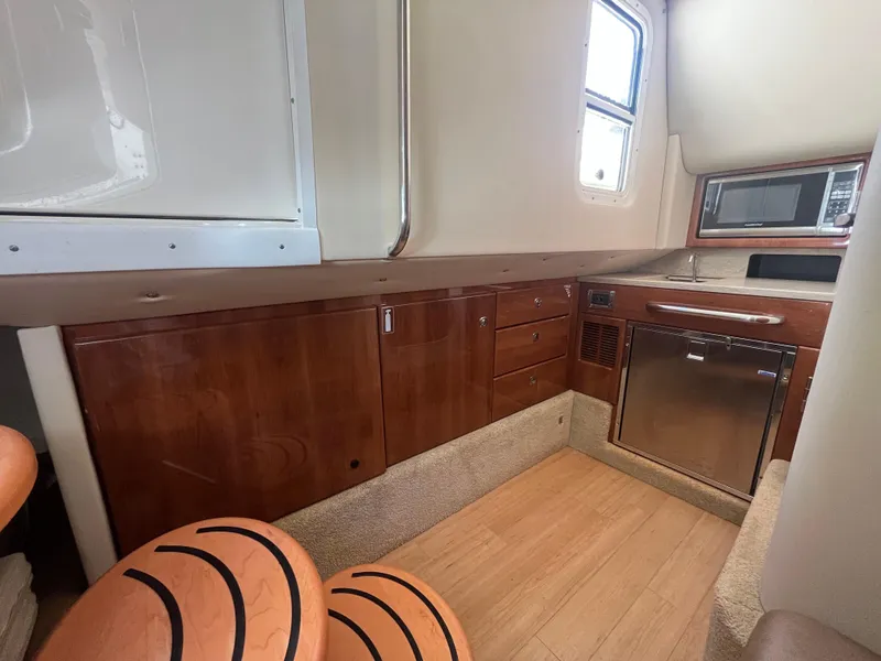 Slide: The Image of 2014 Formula 350 Crossover Bowrider interior with wood cabinets and compact kitchen area. - 18