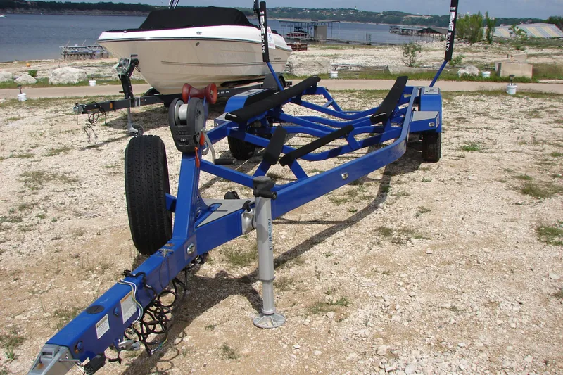 Slide: The Image of Blue boat trailer for 2017 Malibu Wakesetter 24 MXZ on rocky lakeside terrain. - 16