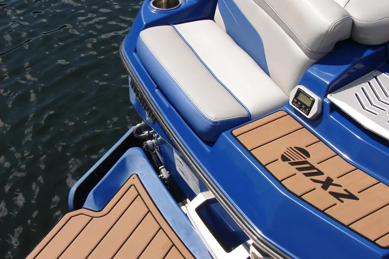 Slide: The Image of 2017 Malibu Wakesetter 24 MXZ boat with blue and white seating, teak deck, and water backdrop. - 20