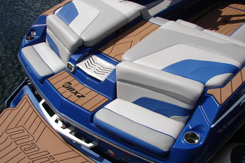 Slide: The Image of 2017 Malibu Wakesetter 24 MXZ boat with blue and white seating on water. - 21