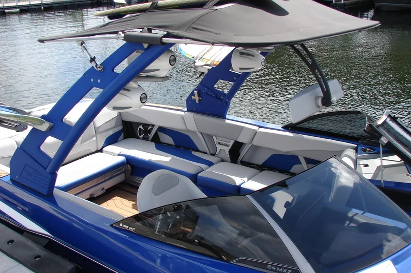Slide: The Image of 2017 Malibu Wakesetter 24 MXZ boat with blue and white interior on the water. - 24