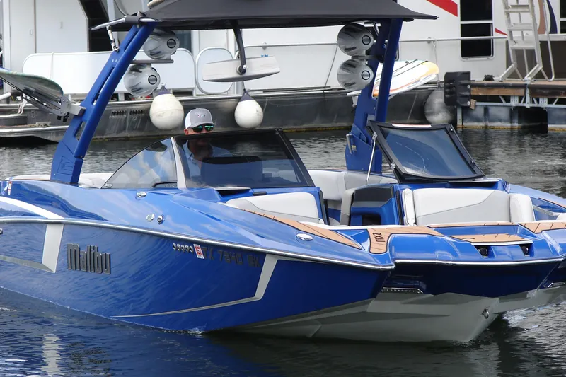 Slide: The Image of 2017 Malibu Wakesetter 24 MXZ boat in blue, docked on calm water. - 9