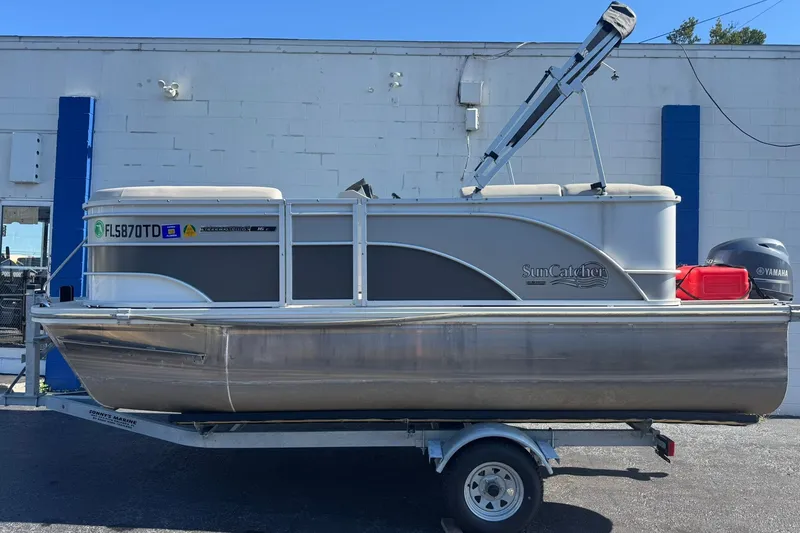 The Image of 2022 SunCatcher Select 16C pontoon boat on trailer, parked outside a building. - 0