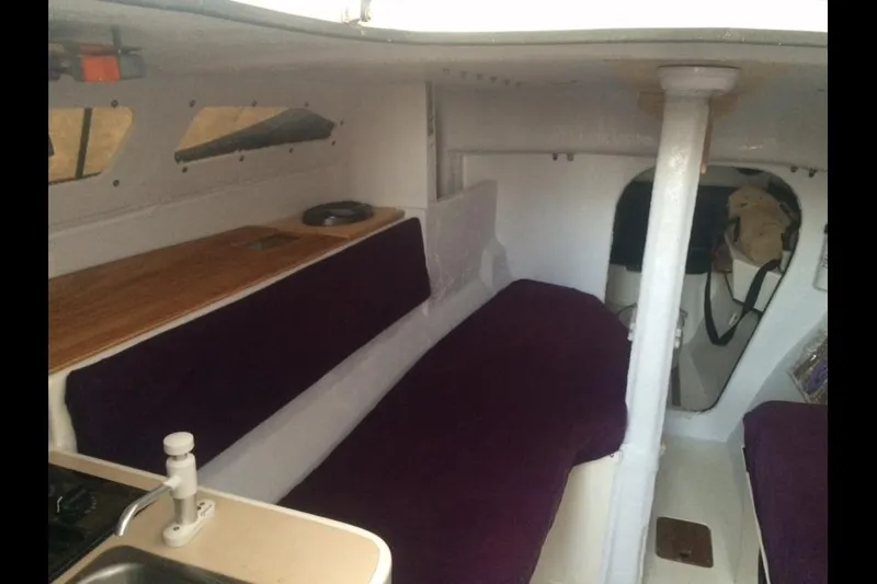 Slide: The Image of Interior of a 1991 Corsair F 27 sailboat with purple cushions and compact layout. - 5