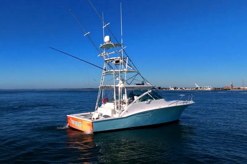 Slide: The Image of 2003 Cabo 40 Express boat cruising on open water under clear blue sky. - 13