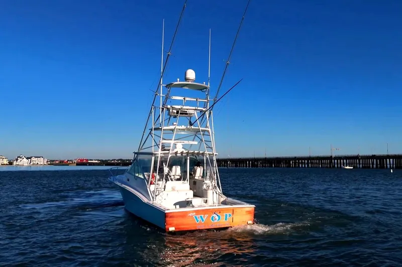 Slide: The Image of 2003 Cabo 40 Express boat cruising on open water near a pier. - 16
