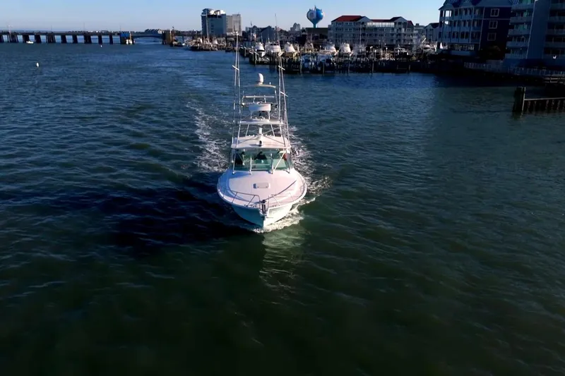 Slide: The Image of 2003 Cabo 40 Express yacht cruising near a marina with cityscape backdrop. - 7