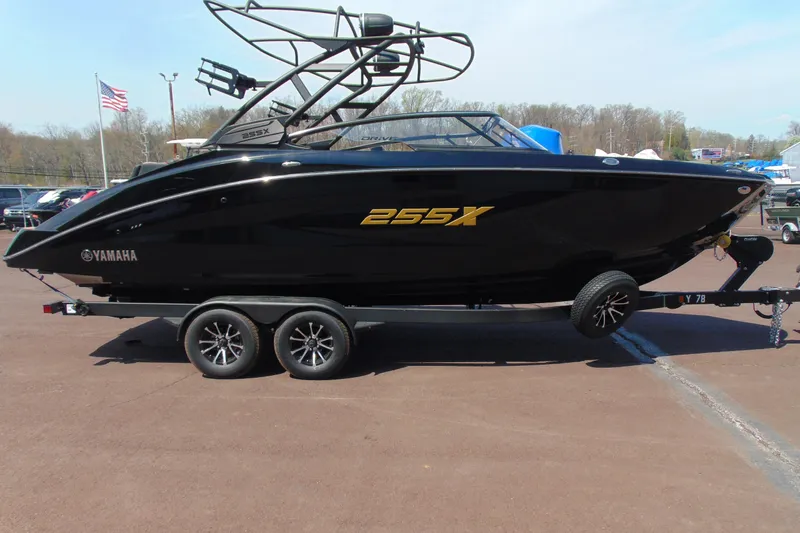 The Image of 2026 Yamaha Boats 255XD in black on trailer, side view with American flag in background. - 0