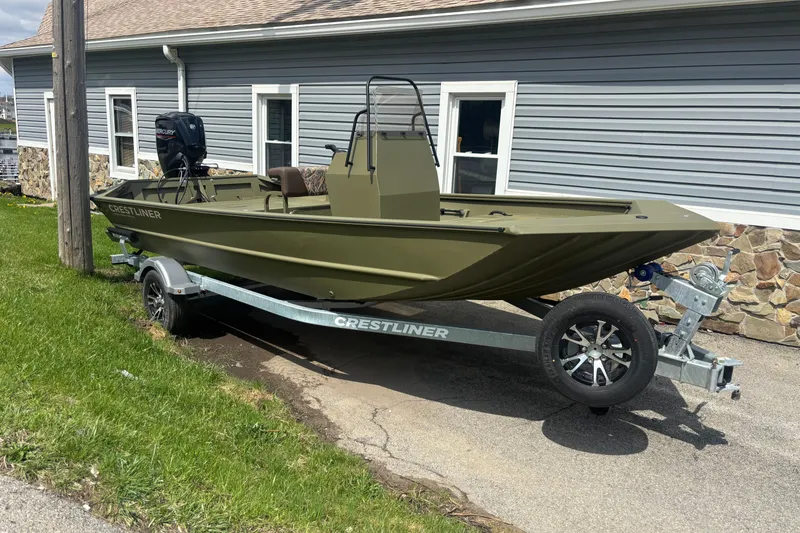 The Image of 2026 Crestliner 1870 Retriever FCC boat on trailer, parked beside a building. - 0