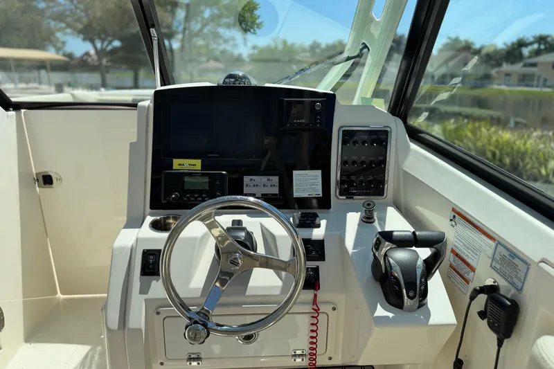 Slide: The Image of 2021 Cobia 280 Dual Console boat dashboard with steering wheel and controls. - 12